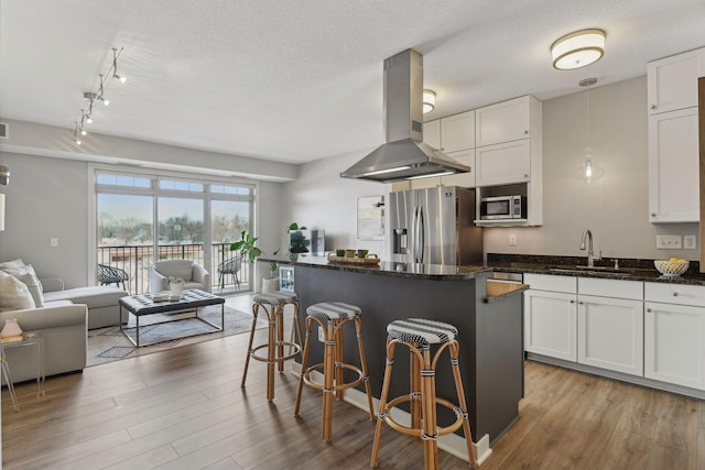 kitchen with sink, appliances with stainless steel finishes, a center island, white cabinets, and island exhaust hood