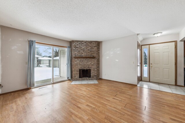 unfurnished living room with a textured ceiling, a fireplace, and light wood-type flooring