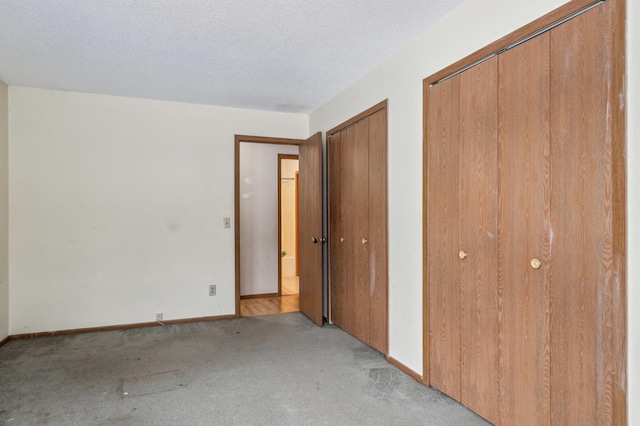 unfurnished bedroom featuring two closets, light colored carpet, and a textured ceiling