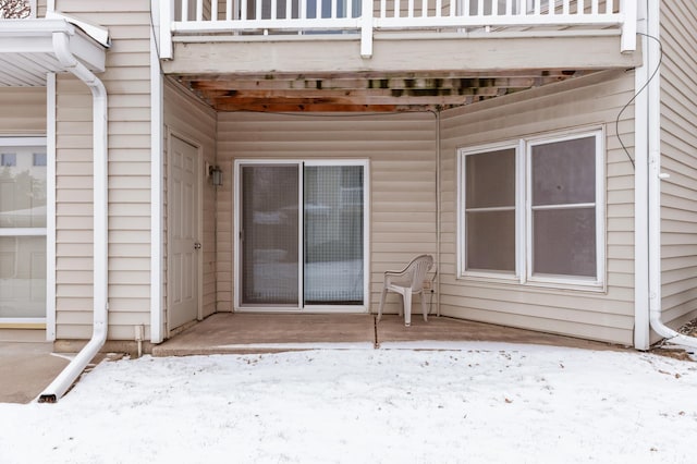 snow covered property entrance featuring a balcony