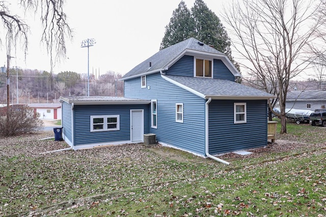 back of property with a yard and central AC unit