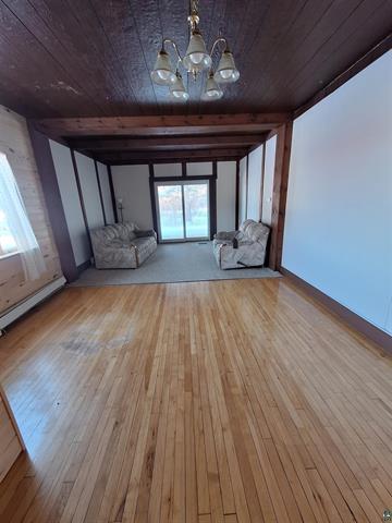 6330 Mitchell Rd, Hughes Twp, WI 54847 - unfurnished living room featuring a notable chandelier, a wealth of natural light, wood ceiling, and light hardwood / wood-style flooring