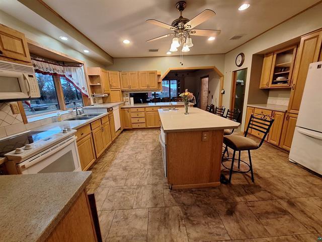 6330 Mitchell Rd, Hughes Twp, WI 54847 - kitchen featuring sink, white appliances, a kitchen island with sink, ceiling fan, and a breakfast bar