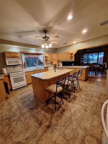 6330 Mitchell Rd, Hughes Twp, WI 54847 - kitchen with sink, white appliances, a kitchen bar, ceiling fan, and a kitchen island