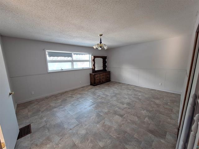 6330 Mitchell Rd, Hughes Twp, WI 54847 - empty room featuring a textured ceiling and a notable chandelier