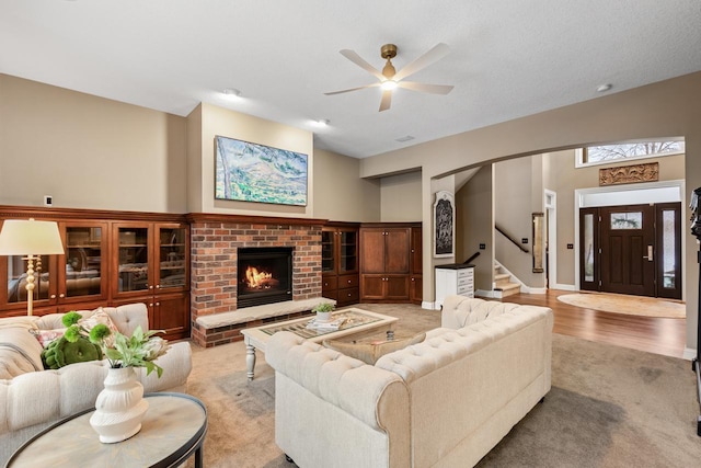 carpeted living room with ceiling fan and a brick fireplace