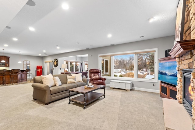 living room featuring bar area, a stone fireplace, and light carpet