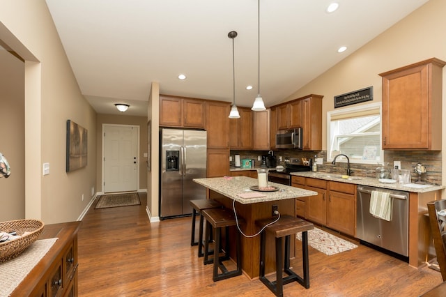 kitchen featuring decorative backsplash, appliances with stainless steel finishes, sink, a kitchen island, and hanging light fixtures