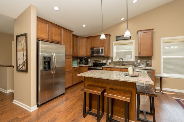 kitchen featuring a breakfast bar, a kitchen island, decorative light fixtures, and appliances with stainless steel finishes