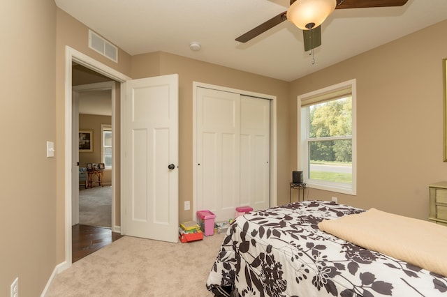 carpeted bedroom with ceiling fan and a closet