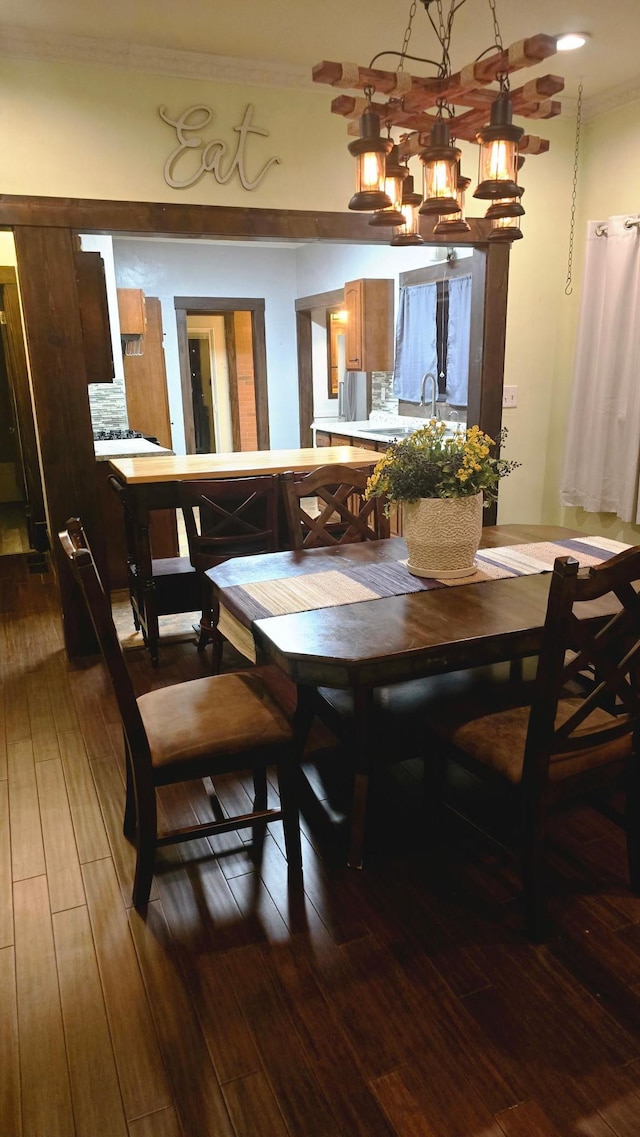 dining space featuring wood-type flooring, ornamental molding, and sink