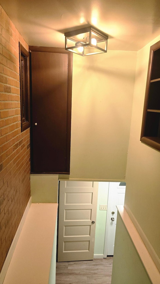 staircase featuring brick wall and wood-type flooring