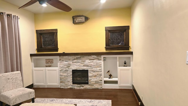 living room featuring dark wood-type flooring, ceiling fan, and a fireplace