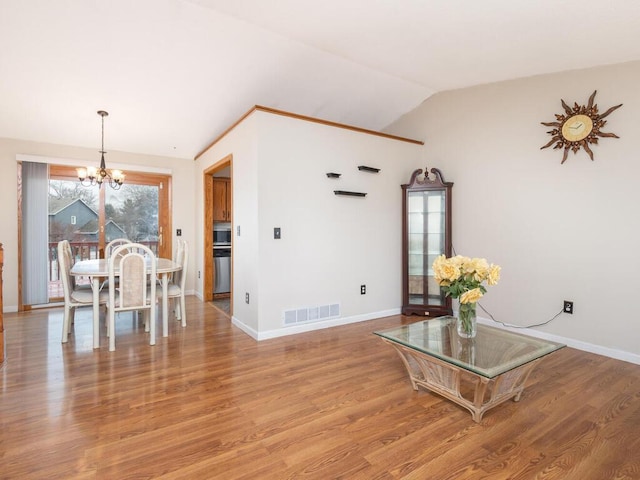 living room with a chandelier, wood-type flooring, and lofted ceiling