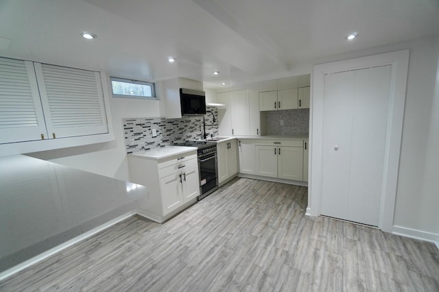 kitchen with backsplash, sink, light hardwood / wood-style flooring, black / electric stove, and white cabinetry