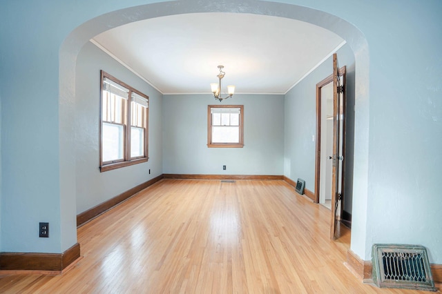 empty room with light wood-type flooring, an inviting chandelier, and ornamental molding