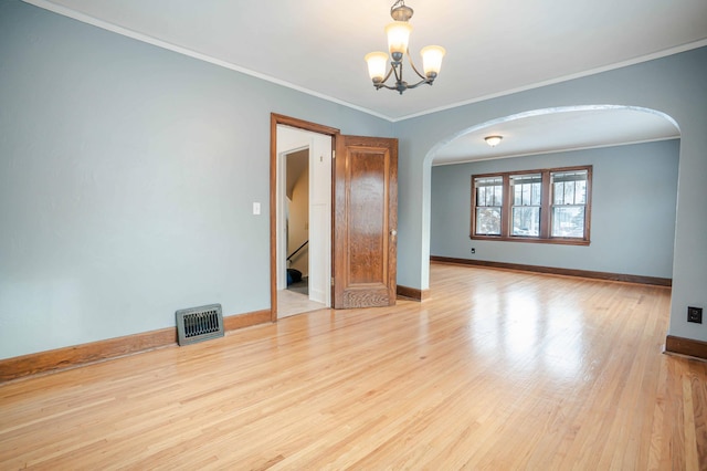 empty room featuring light wood-type flooring, crown molding, and a chandelier