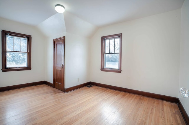 spare room featuring lofted ceiling and light wood-type flooring