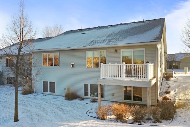 snow covered back of property with a balcony