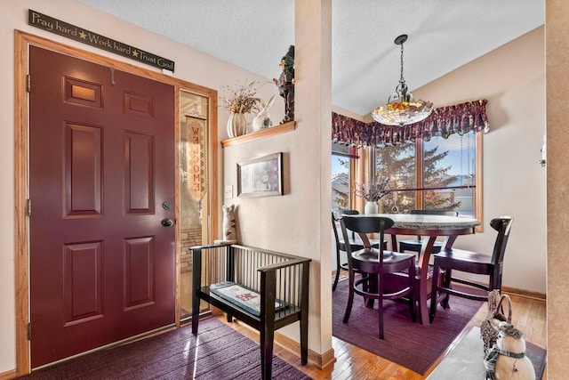 foyer featuring a textured ceiling, hardwood / wood-style floors, and vaulted ceiling