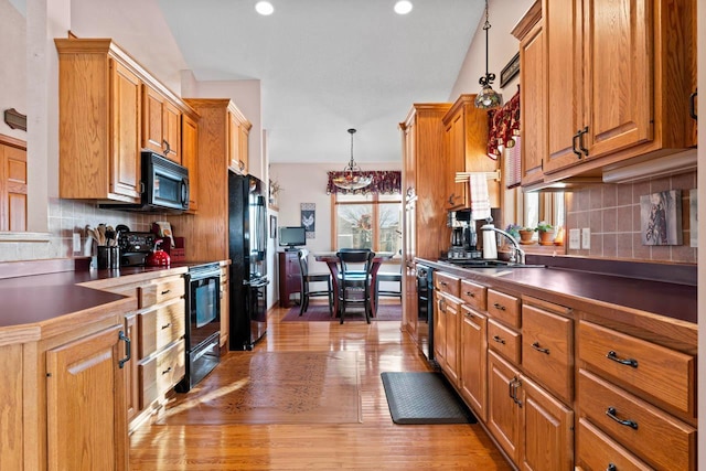 kitchen featuring sink, decorative light fixtures, light hardwood / wood-style floors, decorative backsplash, and black appliances