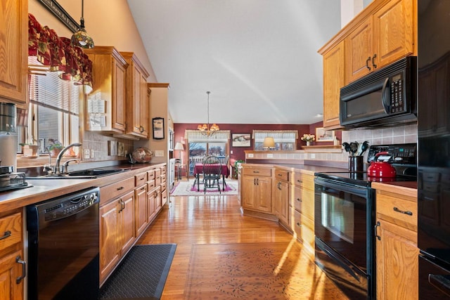 kitchen featuring hanging light fixtures, a notable chandelier, black appliances, decorative backsplash, and sink