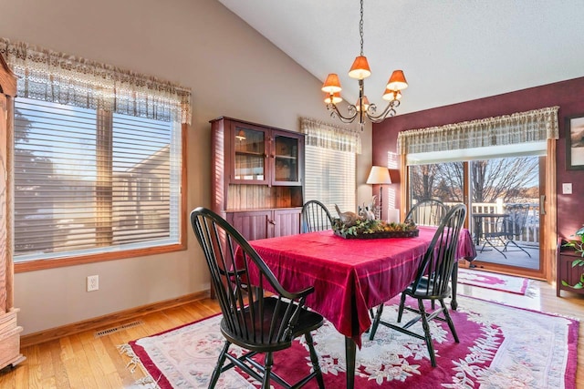 dining room with lofted ceiling, an inviting chandelier, and light hardwood / wood-style flooring