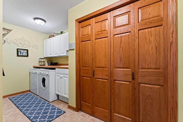 washroom featuring a textured ceiling, cabinets, washing machine and dryer, and light tile patterned floors