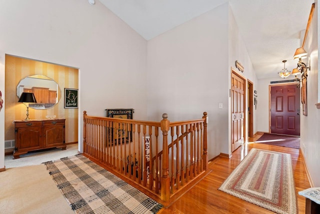 hall with high vaulted ceiling, an inviting chandelier, and light wood-type flooring