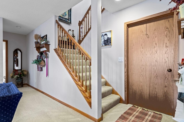 stairway featuring carpet floors and a textured ceiling