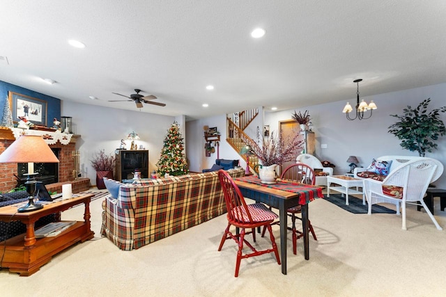 carpeted dining area featuring ceiling fan with notable chandelier, a textured ceiling, and a fireplace