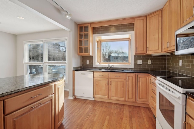 kitchen with white appliances, light hardwood / wood-style flooring, track lighting, backsplash, and sink