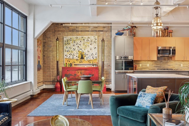 kitchen featuring decorative light fixtures, a notable chandelier, brick wall, appliances with stainless steel finishes, and decorative backsplash