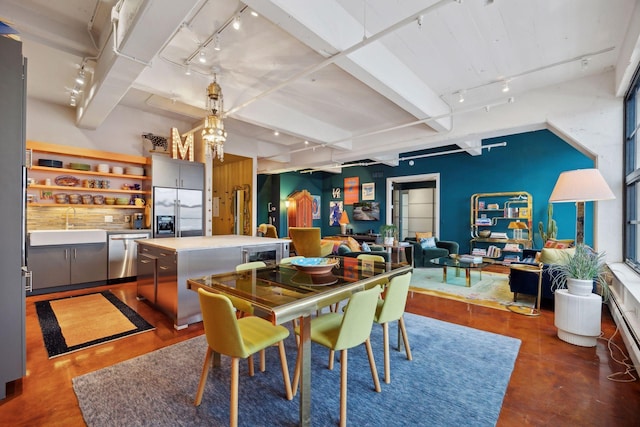 dining space with sink, rail lighting, and beam ceiling