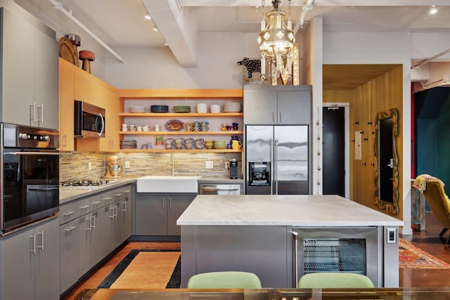 kitchen with sink, pendant lighting, a kitchen island, wine cooler, and stainless steel appliances