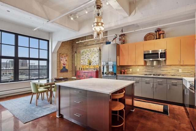 kitchen featuring appliances with stainless steel finishes, hanging light fixtures, a breakfast bar area, decorative backsplash, and a kitchen island