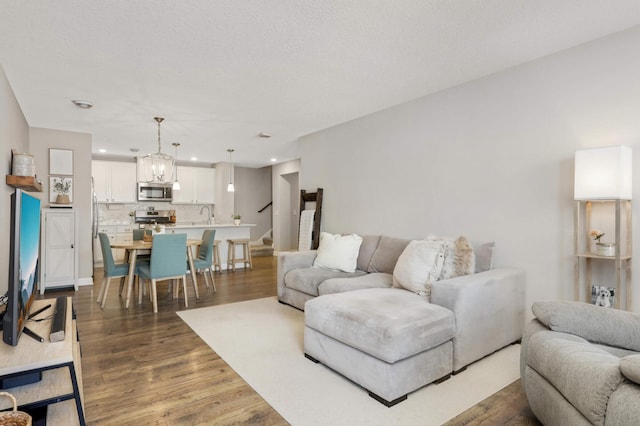 living area with dark wood-type flooring, recessed lighting, a textured ceiling, and stairs