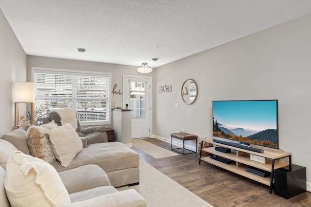 living area with a textured ceiling, baseboards, and wood finished floors