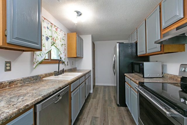 kitchen with sink, stainless steel appliances, a textured ceiling, and dark wood-type flooring