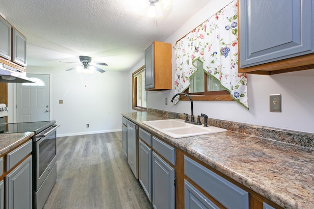 kitchen featuring stainless steel appliances, ceiling fan, a textured ceiling, dark wood-type flooring, and sink