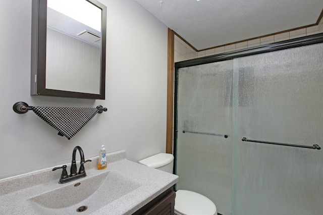 bathroom featuring toilet, a textured ceiling, a shower with shower door, and vanity