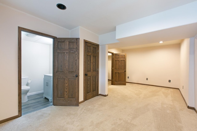 unfurnished bedroom featuring connected bathroom and light carpet