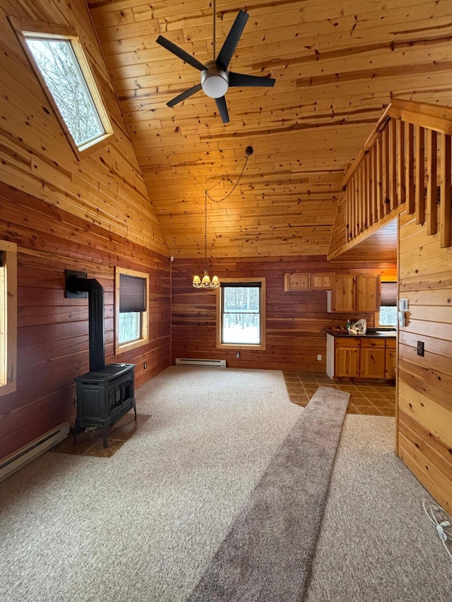 carpeted living room featuring wood ceiling, ceiling fan with notable chandelier, a wood stove, and a baseboard radiator