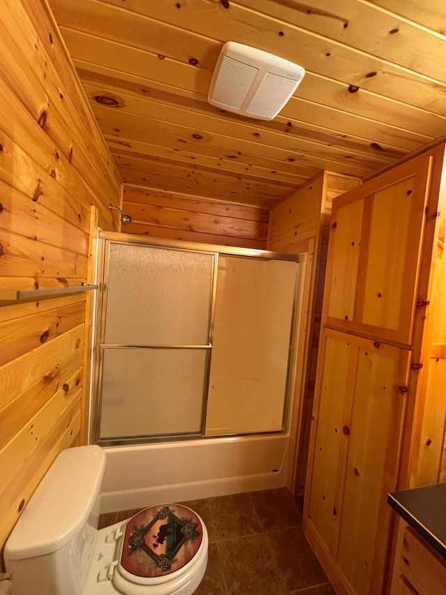 bathroom featuring wooden ceiling, toilet, shower / bath combination with glass door, and wooden walls