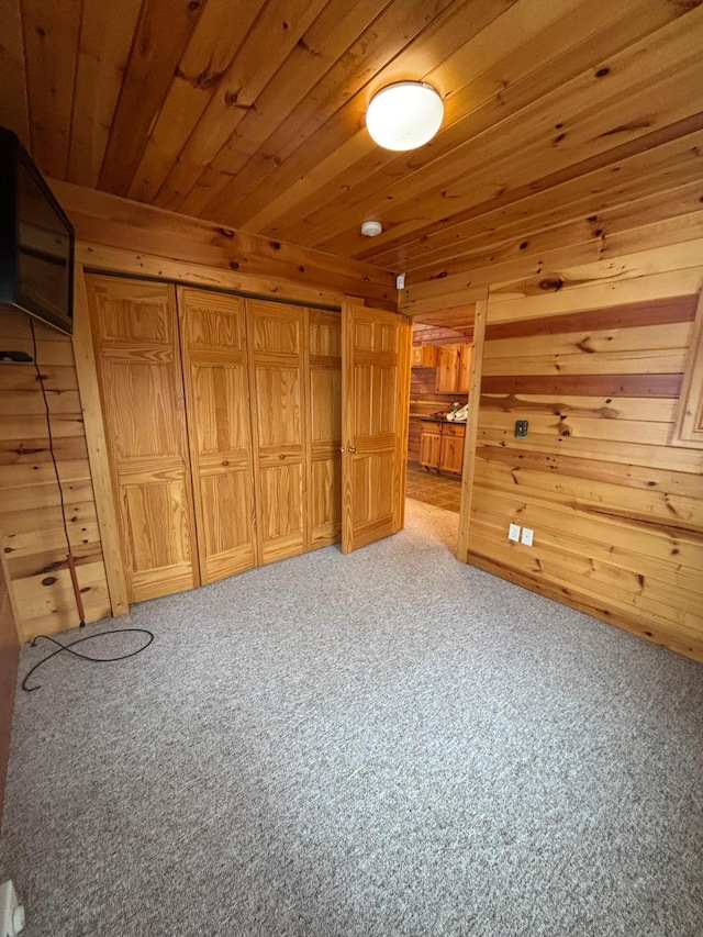 additional living space with carpet, wood walls, and wooden ceiling