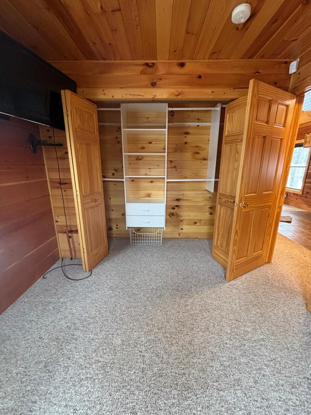 unfurnished bedroom with wood ceiling, wood walls, and carpet floors