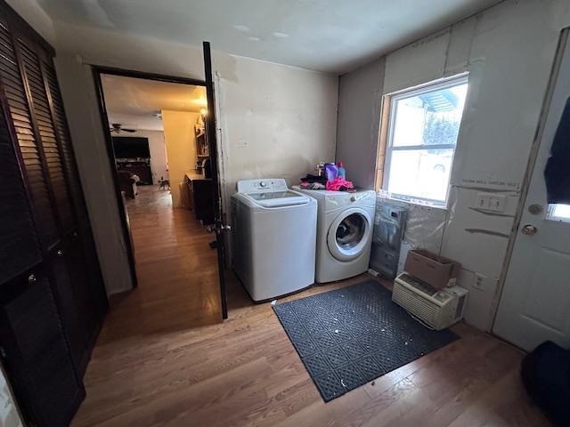 clothes washing area featuring light wood-type flooring, washing machine and dryer, and ceiling fan