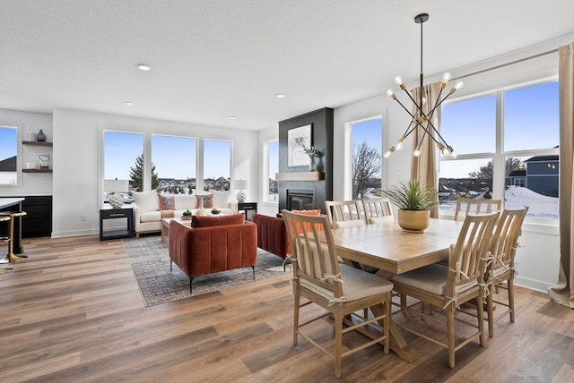 dining area with hardwood / wood-style flooring, an inviting chandelier, a wealth of natural light, and a fireplace