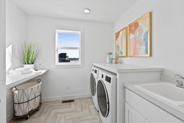 laundry room featuring sink, light parquet floors, and separate washer and dryer