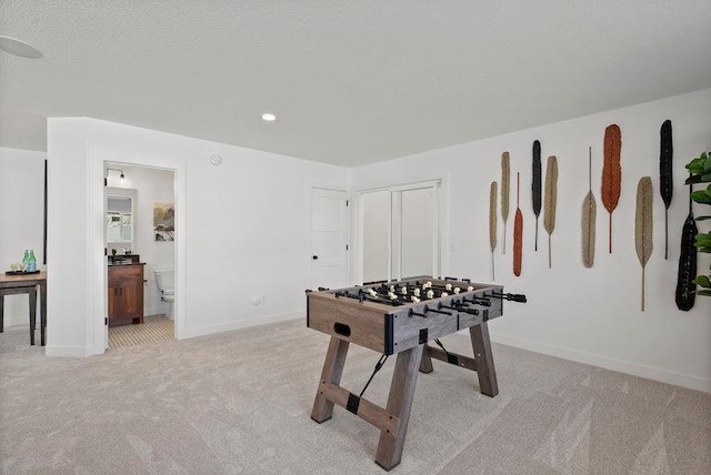 recreation room featuring light colored carpet and a textured ceiling